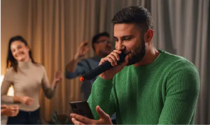 Image of man in green sweater singing into microphone